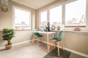 een keuken met een tafel, stoelen en ramen bij FineApartment Alt Duvenstedt in Alt Duvenstedt