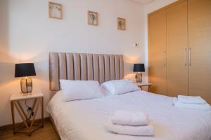 um quarto com uma cama branca com duas toalhas em Appartement luxueux Prestigia em Rabat