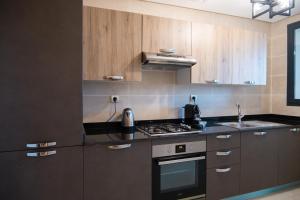 een keuken met houten kasten en een fornuis met oven bij Appartement luxueux Prestigia in Rabat