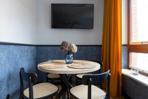 a table with chairs and a vase with flowers on it at Homewell Apartments Czartoria- free parking in Poznań