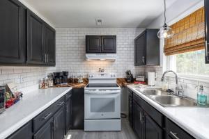 a kitchen with black cabinets and a white stove top oven at Chic 2BR Durham Haven - Walk to Duke in Durham