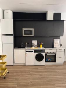 a kitchen with white appliances and a black wall at Exyca Metropolitano in Madrid