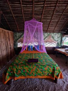 Cette chambre comprend un lit à baldaquin. dans l'établissement Mahana Tua Lodge Huahine, à Puahua