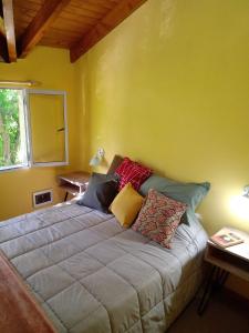 Cama en habitación con pared amarilla en Mi Casa Tu Casa en Lago Puelo