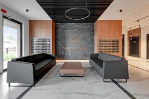 a lobby with two black leather chairs and a chalkboard at Nadmotławie Deluxe 3 Sauna & Siłownia by Grand Apartments in Gdańsk