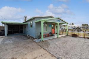 una piccola casa blu con un portico accanto a una recinzione di Flamingo Bay Cottage cottage a Saint James City