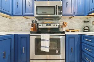 una cucina con mobili blu e un fornello con forno a microonde di Flamingo Bay Cottage cottage a Saint James City