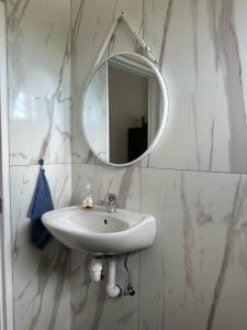 a white bathroom with a sink and a mirror at F2 Farmhouse in Omuthiya