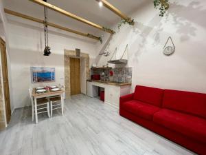 uma sala de estar com um sofá vermelho e uma cozinha em CASA MASADA em Nápoles