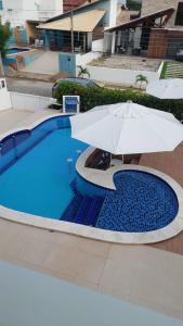 ein Regenschirm neben einem Pool in der Unterkunft OTIMA CASA BARRA S MIGUEL AL REVEILLON e JANEIRO 2024 MINIMO 05 DIARIAS in Barra de São Miguel