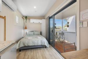 a bedroom with a bed and a balcony at Tiny House Stays House 4 in Sanctuary Point