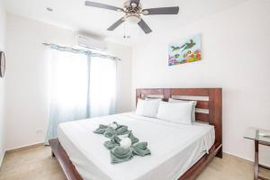a bedroom with a white bed with a ceiling fan at Spotless 3 BRs house w/ pool in Roatán