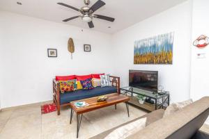 a living room with a blue couch and a tv at Spotless 3 BRs house w/ pool in Roatán