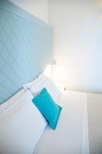 um quarto com uma cama branca e uma almofada azul em Pietrablu Resort & Spa - CDSHotels em Polignano a Mare