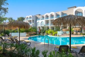 um resort com uma piscina com cadeiras e guarda-sóis em Lindos Breeze Beach Hotel em Kiotari