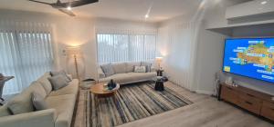 a living room with a couch and a large screen tv at Beach House Yeppoon - ARay at Cooee Bay - Apt A in Yeppoon