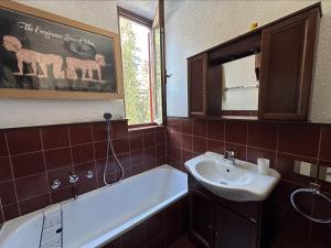 La salle de bains est pourvue d'une baignoire, d'un lavabo et d'un miroir. dans l'établissement Appartamento Patascoss, à Madonna di Campiglio