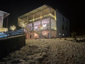 ein Gebäude mit einer Treppe im Schnee in der Nacht in der Unterkunft Guesthouse SHAMPRIANI in Mestia