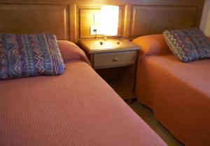 Habitación con 2 camas y mesa con lámpara. en Casa Rural Rebost, en Sant Llorenç de Morunys