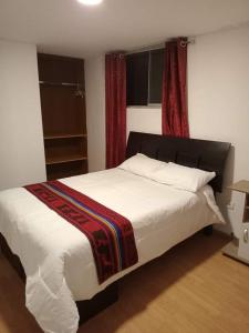 a bedroom with a large bed with a red curtain at Paucartambo wasichay hostal in Cusco