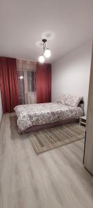 a bedroom with a bed and a red curtain at Warm Apartament Nou in Bacău