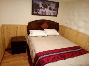 a bedroom with a bed with a wooden head board at Paucartambo wasichay hostal in Cusco