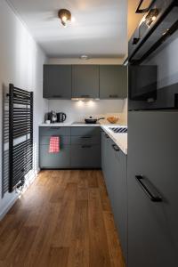 uma cozinha com armários cinzentos, pisos em madeira e um frigorífico em luxe vakantiehuisje - sauna - natuur - strand em Ewijk