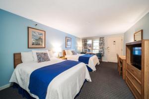 a hotel room with two beds and a flat screen tv at Stage Run by the Sea in Ogunquit