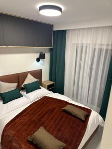 a bedroom with a large bed with two pillows on it at Apartamenty Czarne Owce in Szklarska Poręba