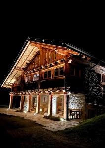 una casa de madera por la noche con luces encendidas en Maroc Mountain Chalet en Madonna di Campiglio