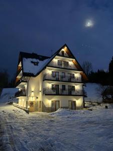 un edificio iluminado en la nieve por la noche en Willa Nosalowa Dolina, en Zakopane