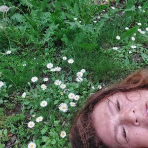 uma mulher deitada na relva ao lado de flores em Cvrkut Ptica 1 em Mladenovac