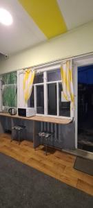 a room with two windows with yellow and white curtains at Roots Hostel in Chişinău