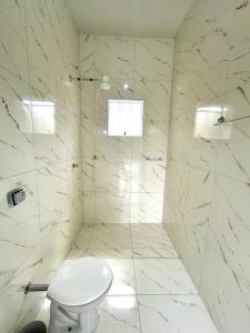 y baño blanco con aseo y ducha. en Chácara Primavera en Monte Sião