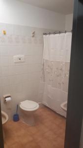 y baño con aseo y cortina de ducha. en Mi Casa en Villa Carlos Paz