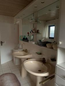 uma casa de banho branca com 2 lavatórios e um espelho em Ferienwohnung Marell em Großwallstadt