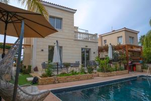 a house with a swimming pool and an umbrella at Villa Myria in Paphos City