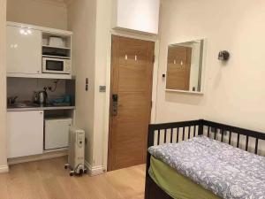 een kleine slaapkamer met een bed en een keuken bij Soho China Town Rooms in Londen