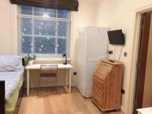 1 dormitorio con escritorio, 1 cama y ventana en Soho China Town Rooms, en Londres