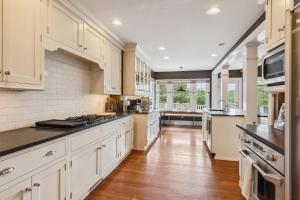 a large kitchen with white cabinets and wooden floors at Modern Provincial Farmhouse I Outdoor Oasis in Chagrin Falls