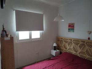 een slaapkamer met een rood bed en een raam bij Departamento Mar del Plata, La Perla in Mar del Plata