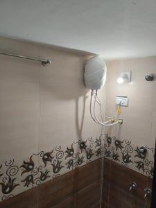 La salle de bains est pourvue d'une lumière sur le mur et d'un mur avec aigre. dans l'établissement Ashapura Home Stay, à Kevadia