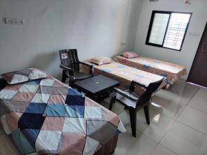 Cette chambre comprend deux lits, une table et des chaises. dans l'établissement Ashapura Home Stay, à Kevadia