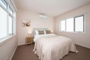a white bedroom with a bed and two windows at Barefoot Beach House McCrae in McCrae