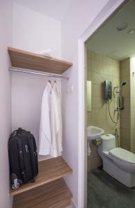 a bathroom with a suitcase and a toilet and a sink at Sovotel Uptown 101 in Petaling Jaya
