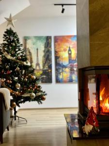 a christmas tree in a living room with a fireplace at Villa Pluto in Gjilan