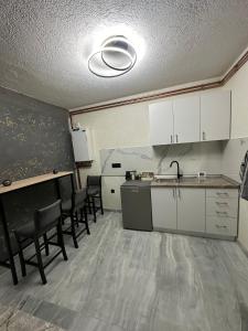 uma cozinha com armários brancos e cadeiras num quarto em Lavanda Apartman em Novi Pazar