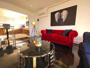 a living room with a red couch and a glass table at Luxus im Himmel. 3Zimmer, Parkplatz, 22 Stock in Mülheim an der Ruhr