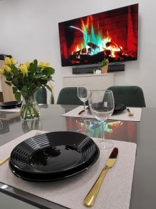 uma mesa com um prato e copos e uma lareira em Luksusowy Apartament Sucumin 95mkw 