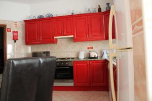 una cocina roja con electrodomésticos negros y armarios rojos en Moradia Bela House, en Santa Cruz 13 fotos más